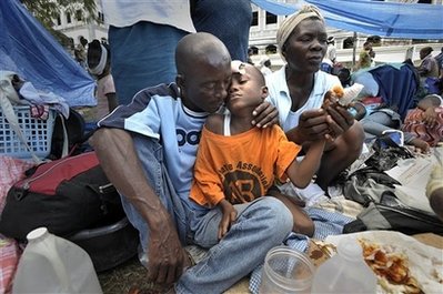 A boy is embraced by his father after receiving first aid on his hand as they use Park Boyer as their new home in the Petionville neighborhood of Port-au-Prince on Saturday, Jan. 16, 2010. (AP Photo/Sun-Sentinel, Michael Laughlin) MANDATORY CREDIT: SUN-SENTINEL, MICHAEL LAUGHLIN; MAGS OUT