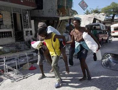 A resident carries an injured person for medical assistance after a major earthquake hit Port-au-Prince, January 13, 2010. Thousands were feared dead in the major earthquake that destroyed the presidential palace, schools, hospitals and hillside shanties in Haiti, its leaders said on Wednesday, and the United States and other nations geared up for a big relief operation. by REUTERS/Carlos Barria (HAITI - Tags: DISASTER ENVIRONMENT)