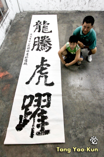 Little Tang (Tang Yao-Kun) with his Chinese calligraphy writing, "dragon leaps, tiger jumps". Behind is the teacher Mr. Liu Ming-Ling. 