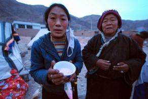 A Tibetan resident of Jiegu, Yushu County, in northwest China's Qinghai province shows all she has to eat - a bowl of barley - amid the rubble of their demolished homes on April 15, 2010. (Photo courtesy: AFP)