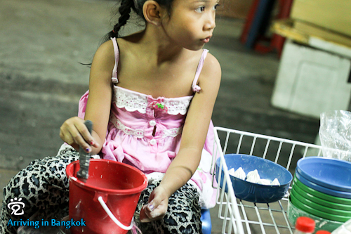 A little Thai girl was mixing the powder cubes with water, to be used for smearing others during the festival