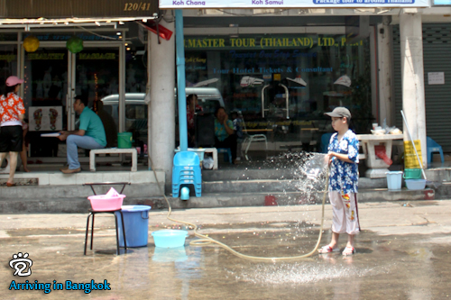 A kid with a water hose in hand waiting for prey