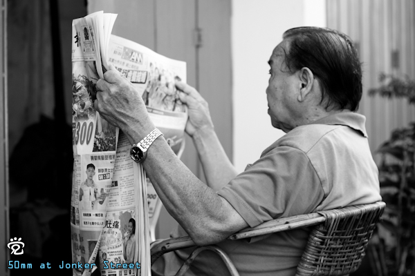 an uncle staying at Tukang Besi Street was reading a Chinese newspaper