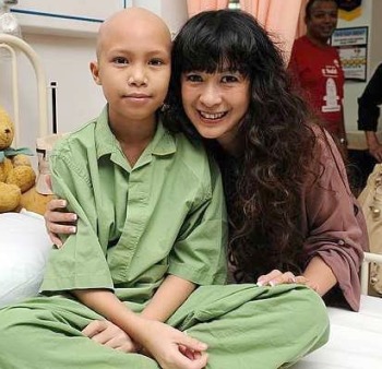 Source of courage: Lorna meeting a child in the Sarawak General Hospital before she shaved her head. (photo: The Star)