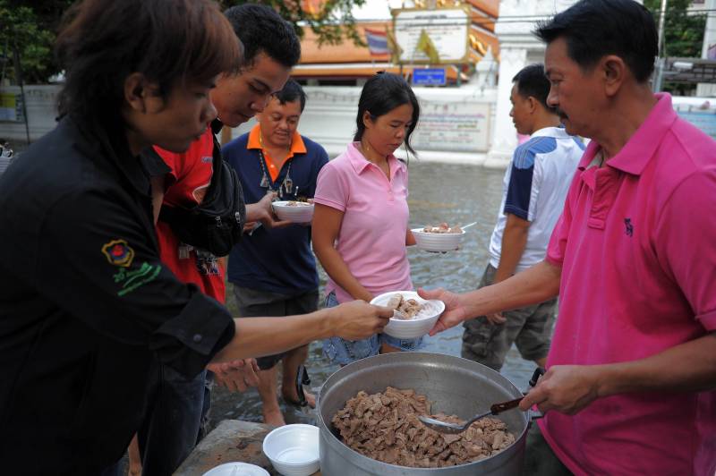 遭遇水劫不忘施恩行善。泰国一户人家Ratanasunya Teerachat在居住的受灾区提供食物賑济灾民，为灾民带来一丝暖意。（图：法新社）