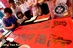 Little Tang was writing at the Jonker Street of Melaka for a charity event. Little Tang's cute sister and father were just standing beside him.