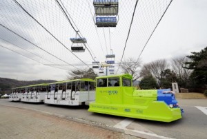 The Online Electric Vehicle (OLEV), towing three carriages, runs along a blue line under which power strips are buried for recharging, at an amusement park in Gwacheon, south of Seoul. S.Korean researchers launched an environmentally-friendly public transport system using a "recharging road" -- with a vehicle sucking power magnetically from buried electric strips. Photograph by: Jung Yeon-Je, AFP