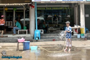 A kid with a water hose in hand waiting for prey