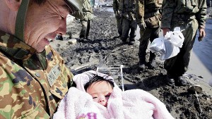 A Self Defense Forces soldier holds a 4-month-old baby in Ishinomaki city in Miyagi prefecture Monday. The child survived the tsunami with her family. (AFP/Getty photo)