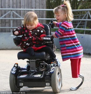 You have a go: Little Ellie is all smiles as she shows a curious Charlotte how to operate the wheelchair