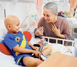HELLO THERE: Lorna having a light moment with a patient at the child cancer unit of the Sarawak General Hospital yesterday. Earlier, Lorna had her head shaven. (Photo courtesy of Datuk Lorna Enan Muloon)