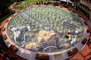 Handout picture taken on June 2, 2011 shows a Greenpeace activist posing for a photo on a 3D artwork representing an organic farm, at the Museum of Siam in Bangkok. Thailand´s rice masterplan recently outlined a policy aimed at keeping Thai rice free of genetically-modified organisms (GMOs). (image from Athit Perawongmetha/AFP/Getty Images)
